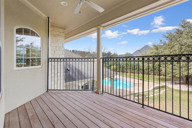 deck with ceiling fan and a fenced in pool