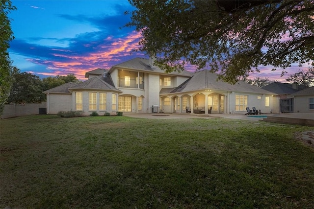 back house at dusk with a yard and a patio