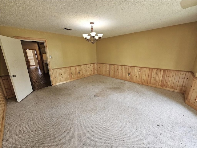 spare room with carpet flooring, a notable chandelier, and a textured ceiling