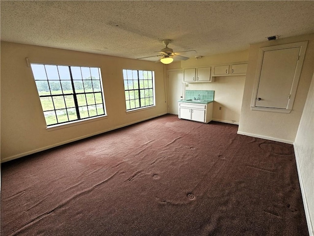 unfurnished living room featuring carpet, a textured ceiling, ceiling fan, and sink