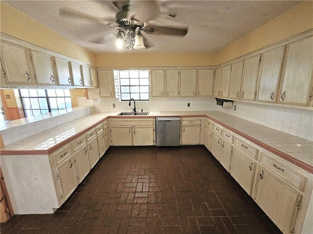 kitchen with ceiling fan, tile counters, dishwasher, sink, and decorative backsplash