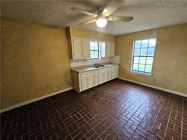 kitchen featuring a textured ceiling, white cabinetry, ceiling fan, and sink