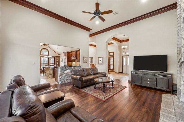 living room featuring dark wood-type flooring, ornamental molding, and ceiling fan with notable chandelier