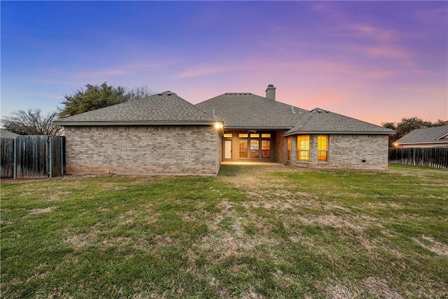 back house at dusk with a lawn