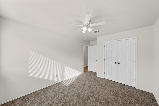 unfurnished bedroom with dark colored carpet, ceiling fan, and a closet