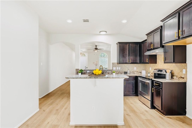 kitchen featuring light stone counters, stainless steel range with electric stovetop, dark brown cabinets, ceiling fan, and a center island