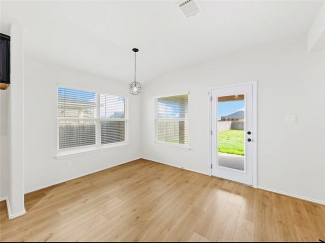 unfurnished dining area featuring a chandelier, plenty of natural light, light hardwood / wood-style floors, and lofted ceiling