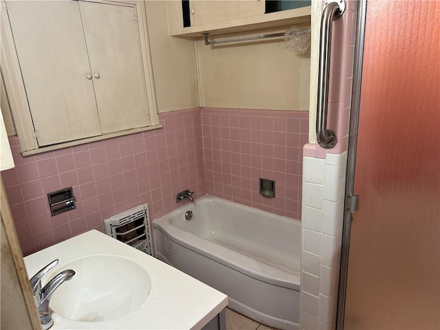 bathroom featuring vanity, a bath, and tile walls