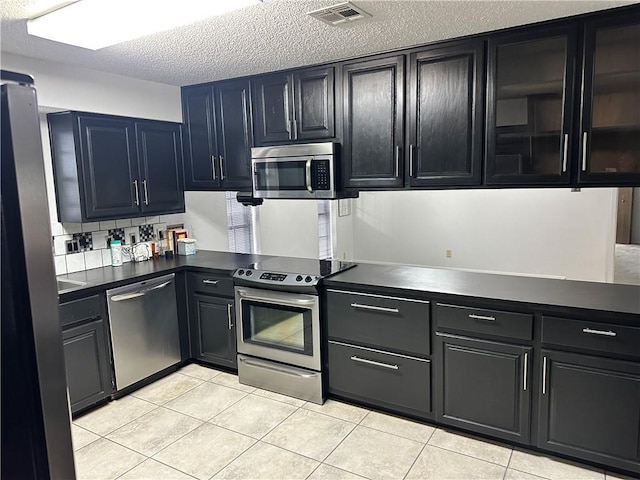 kitchen featuring light tile patterned flooring, a textured ceiling, and appliances with stainless steel finishes