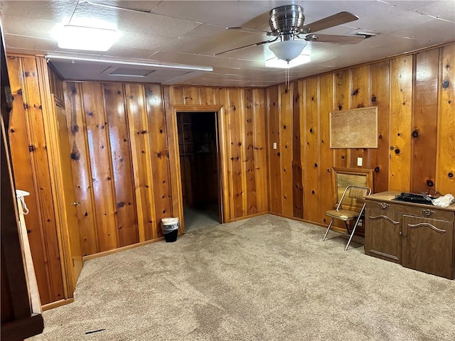 basement with ceiling fan, light carpet, and wooden walls