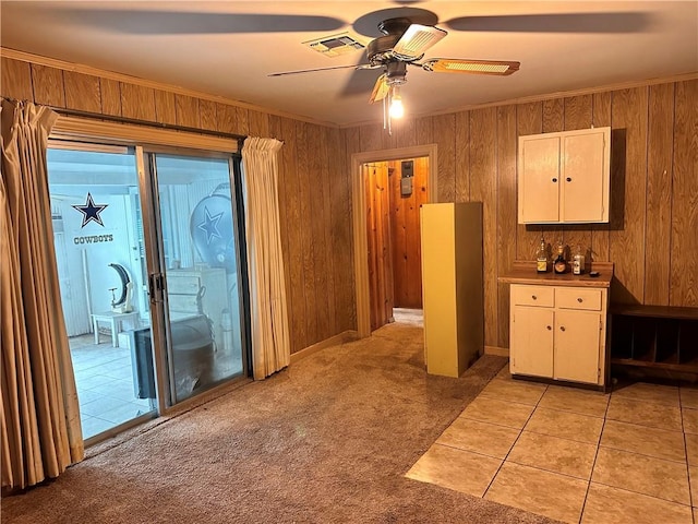 interior space with ceiling fan, wood walls, and crown molding