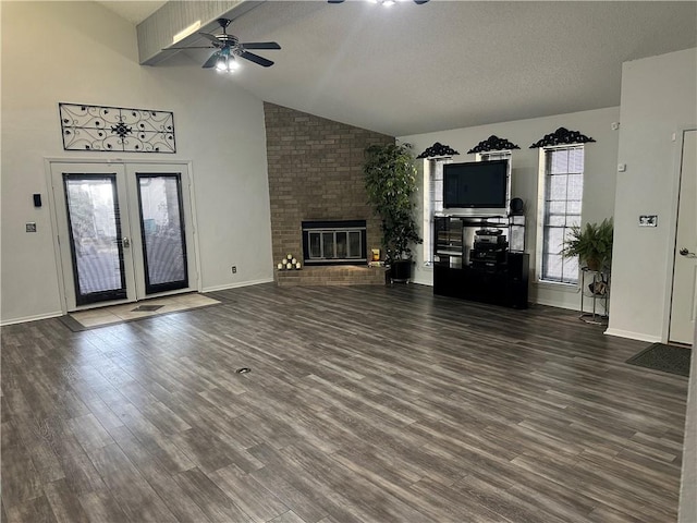 unfurnished living room with ceiling fan, french doors, dark hardwood / wood-style flooring, vaulted ceiling, and a fireplace