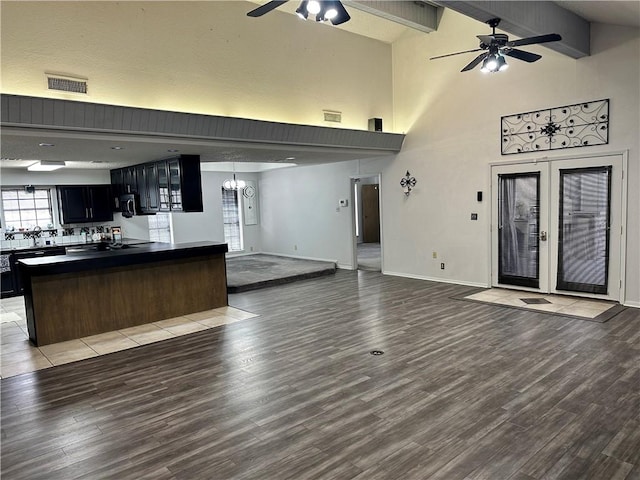 unfurnished living room with high vaulted ceiling, french doors, ceiling fan with notable chandelier, light wood-type flooring, and beamed ceiling