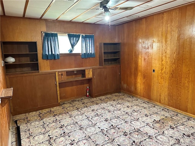 interior space with wood walls and ceiling fan