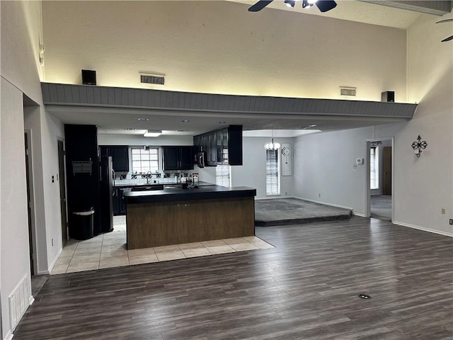 kitchen with a textured ceiling, ceiling fan with notable chandelier, stainless steel appliances, and light hardwood / wood-style flooring