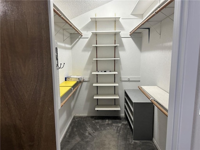 spacious closet featuring dark colored carpet and vaulted ceiling