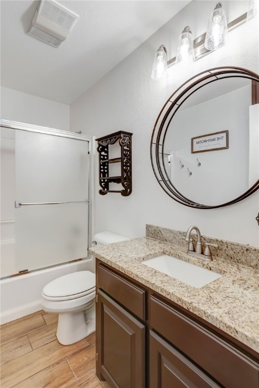 full bathroom with toilet, vanity, enclosed tub / shower combo, and hardwood / wood-style flooring