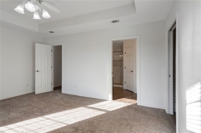 unfurnished bedroom featuring carpet, a raised ceiling, ensuite bath, and ceiling fan