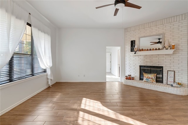 unfurnished living room with ceiling fan, light hardwood / wood-style flooring, and a brick fireplace