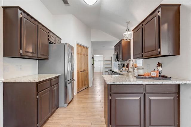 kitchen with dark brown cabinetry, sink, light hardwood / wood-style floors, decorative light fixtures, and appliances with stainless steel finishes