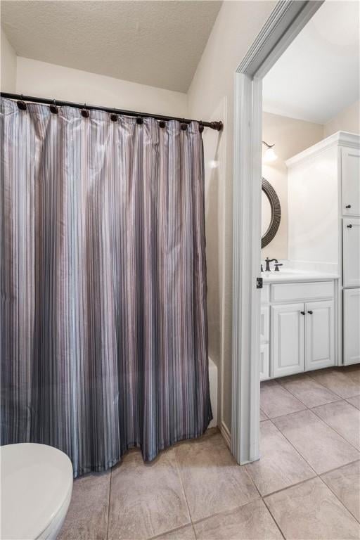 full bathroom featuring vanity, tile patterned floors, shower / bath combination with curtain, toilet, and a textured ceiling