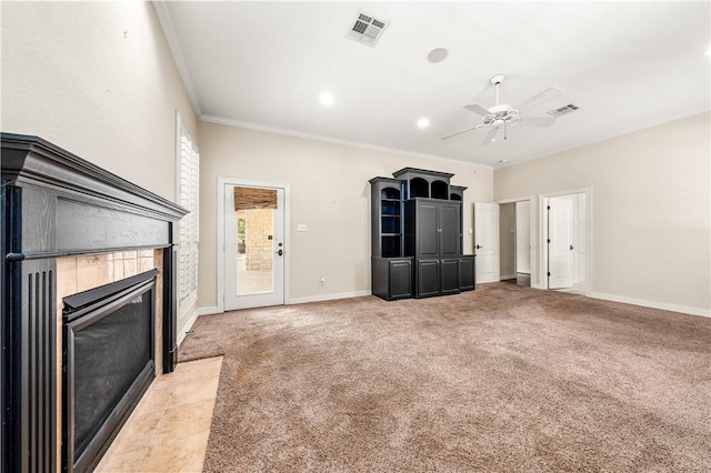 unfurnished living room featuring a tiled fireplace, light carpet, ceiling fan, and ornamental molding