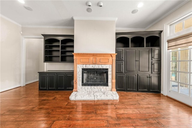 unfurnished living room with a high end fireplace, ornamental molding, and dark wood-type flooring