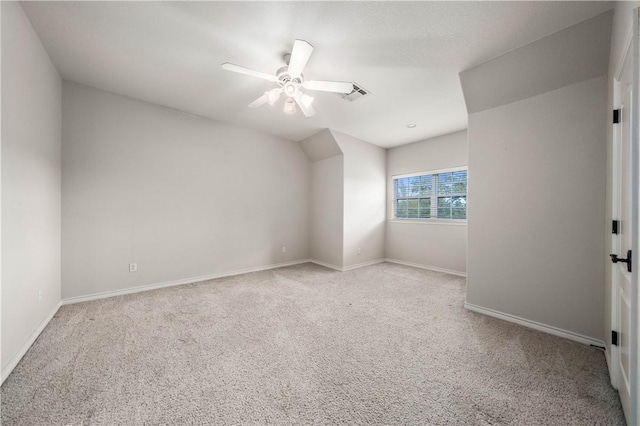 spare room featuring ceiling fan, light colored carpet, and vaulted ceiling