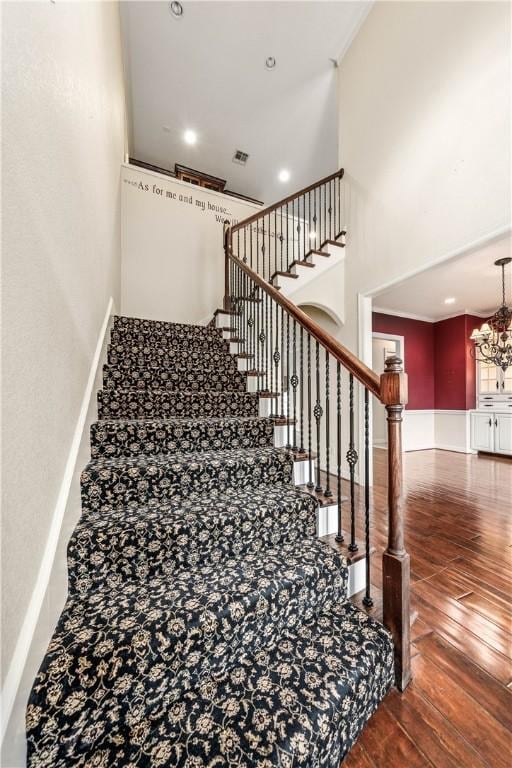 stairs with a notable chandelier, wood-type flooring, and a towering ceiling