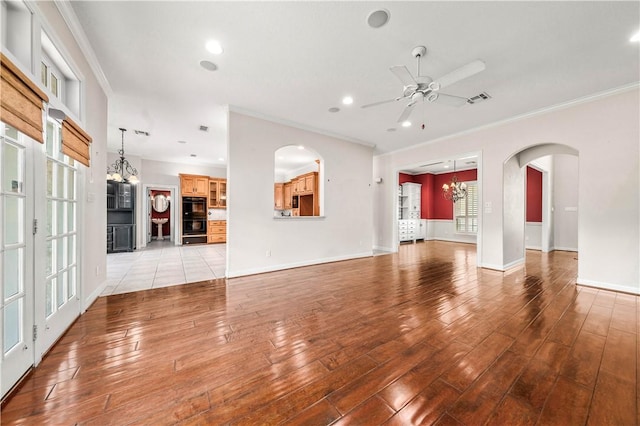 unfurnished living room featuring ornamental molding, ceiling fan with notable chandelier, and light wood-type flooring