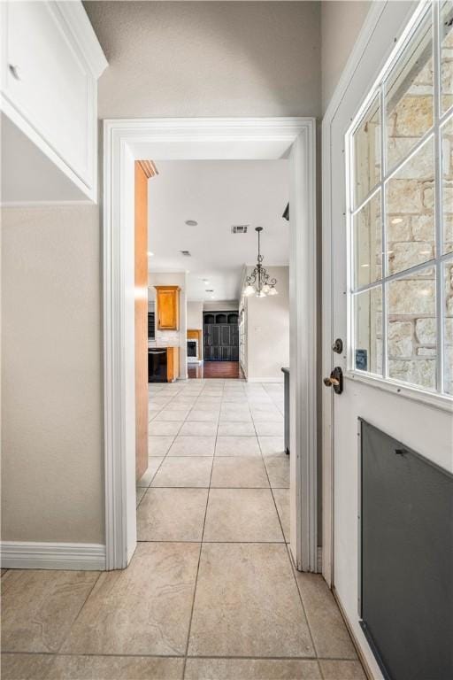 hallway featuring light tile patterned floors and a notable chandelier