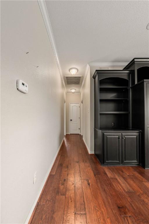 hallway with dark hardwood / wood-style floors and ornamental molding