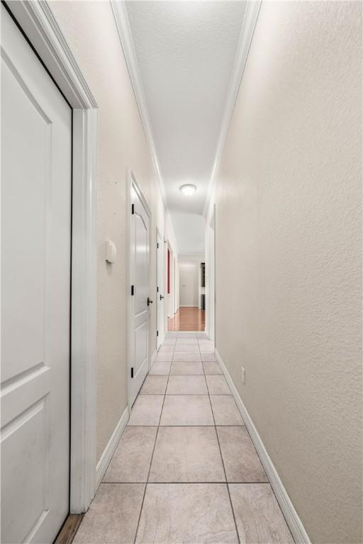 hallway featuring crown molding and light tile patterned floors