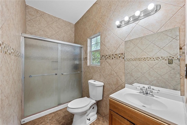 bathroom featuring tile patterned flooring, vanity, a shower with shower door, and tile walls