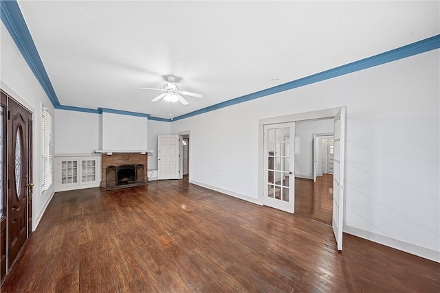 unfurnished living room with french doors, dark hardwood / wood-style flooring, ceiling fan, crown molding, and a fireplace