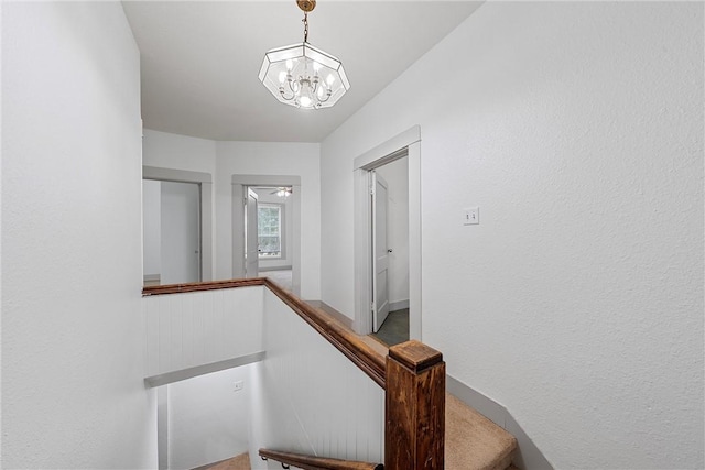 stairs featuring ceiling fan with notable chandelier