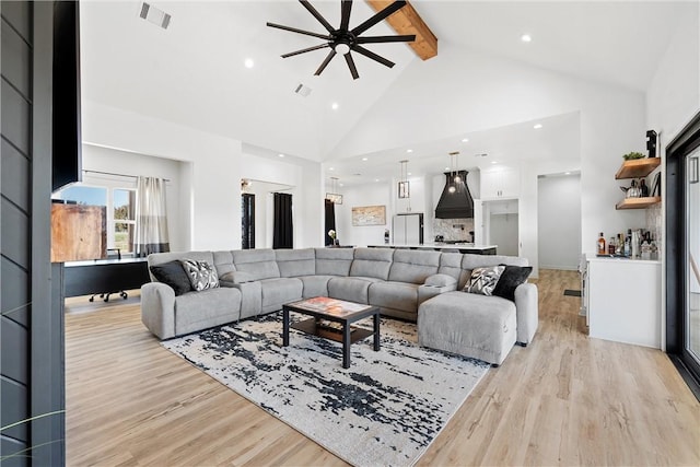 living room featuring beam ceiling, light hardwood / wood-style floors, high vaulted ceiling, and ceiling fan