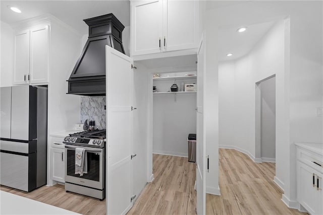 kitchen featuring stainless steel appliances, tasteful backsplash, light hardwood / wood-style flooring, white cabinets, and custom range hood