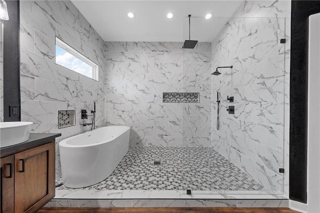 bathroom featuring vanity, independent shower and bath, and tile walls