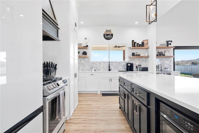 kitchen featuring white cabinets, a healthy amount of sunlight, hanging light fixtures, and stainless steel range with gas stovetop