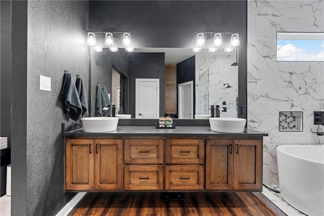 bathroom featuring a washtub, vanity, hardwood / wood-style flooring, and tile walls