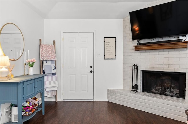 foyer entrance with a brick fireplace and dark hardwood / wood-style floors