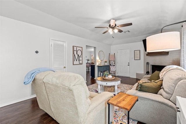 living room featuring ceiling fan, dark hardwood / wood-style flooring, and a brick fireplace