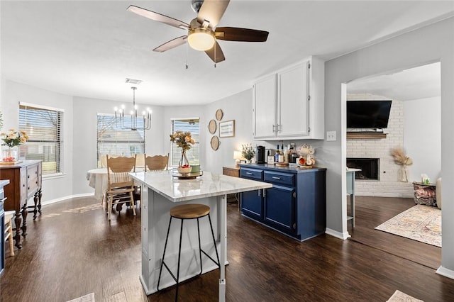 kitchen with dark hardwood / wood-style floors, blue cabinets, white cabinetry, a breakfast bar area, and hanging light fixtures