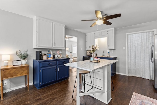 kitchen with a breakfast bar, white cabinets, dark hardwood / wood-style flooring, ceiling fan, and blue cabinetry