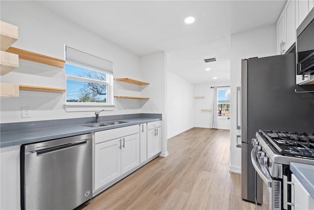 kitchen with white cabinets, stainless steel appliances, light hardwood / wood-style flooring, and sink