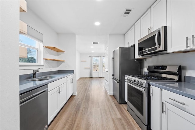 kitchen with sink, white cabinets, stainless steel appliances, and light hardwood / wood-style flooring