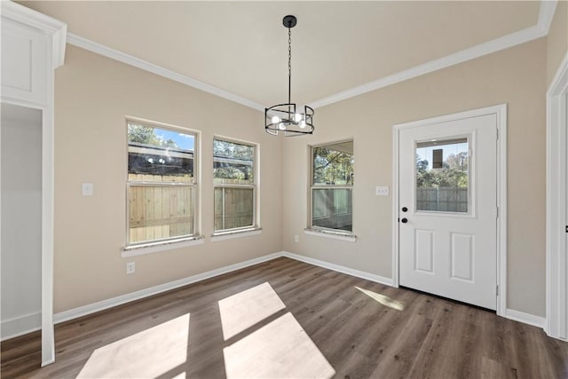 unfurnished dining area with dark hardwood / wood-style floors, crown molding, and a chandelier