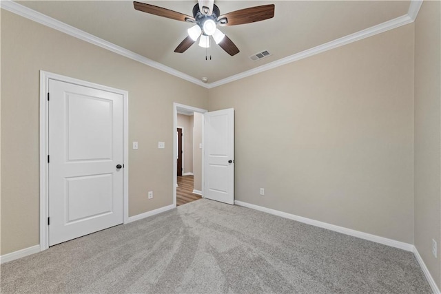 unfurnished bedroom featuring ceiling fan, ornamental molding, and light carpet