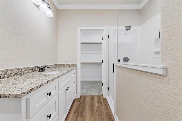 bathroom featuring vanity, hardwood / wood-style flooring, a shower with door, and crown molding